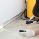 Cockroach pest control in Dubai: technician spraying along kitchen cabinets