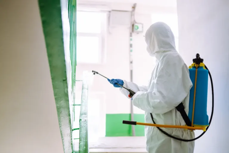 Commercial pest control Dubai: technician in protective suit treating a building stairwell