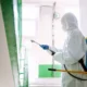 Commercial pest control Dubai: technician in protective suit treating a building stairwell